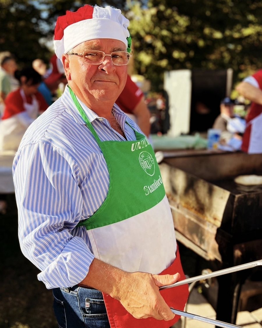 Giorgio Papallo in an Italian tricolor apron and cap, serving at a Stamford community festival
